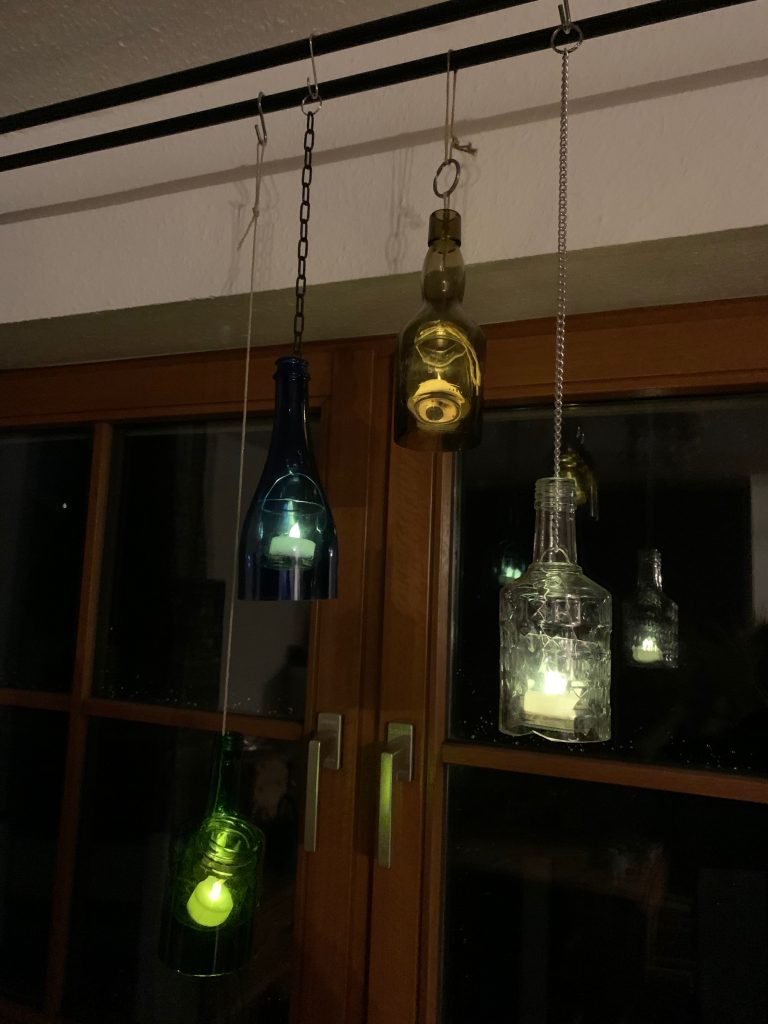 Oberteile von Glasflaschen als Laternen mit LED-Teelichtern